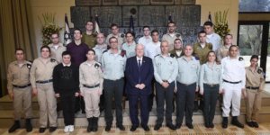 Israeli President Rivlin and Special in Uniform soldiers smile together in front of Israeli flags, standing on steps