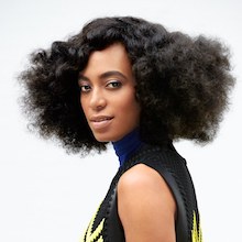 Solange Knowles wearing a black and yellow dress smiling for the camera