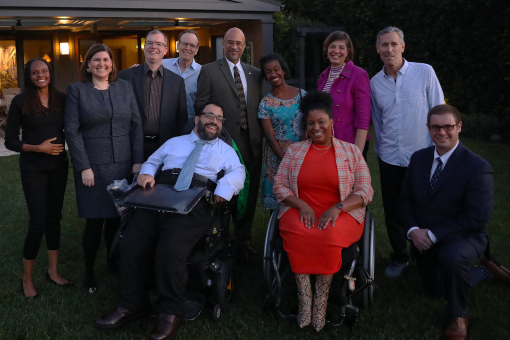 A group of diverse people with and without disabilities smiling together outside