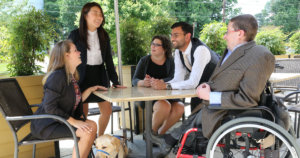 RespectAbility Fellows with disabilities around a table outside, having a conversation
