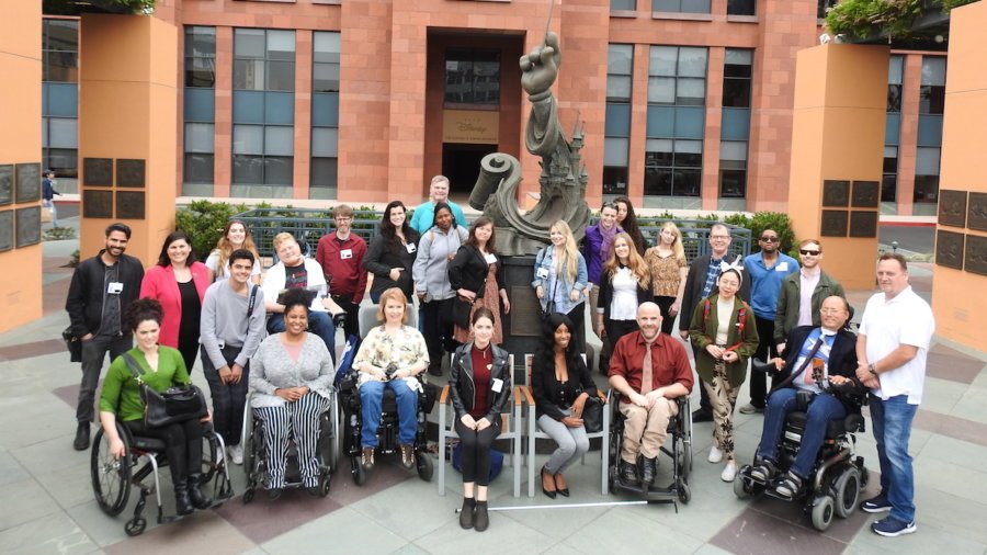 Summer Lab 2019 participants smile together around a statue of Mickey Mouse at The Walt Disney animation studios