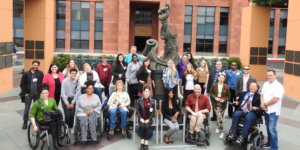 Summer Lab 2019 participants smile together around a statue of Mickey Mouse at The Walt Disney animation studios