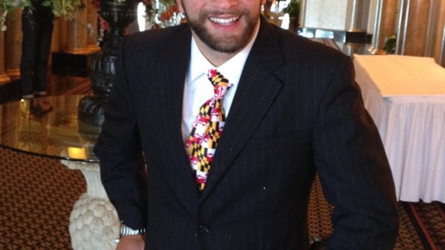 Aaron Kaufman smiling in front of flowers on a table, holding onto his walking frame