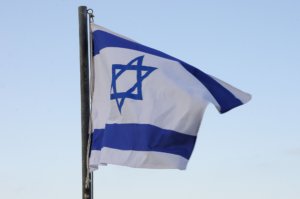 An Israeli flag flying against a blue sky.