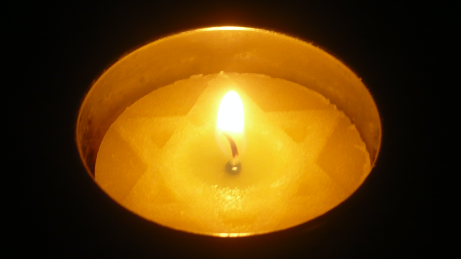 A lit Yom Hashoah candle in a dark room on Yom Hashoah