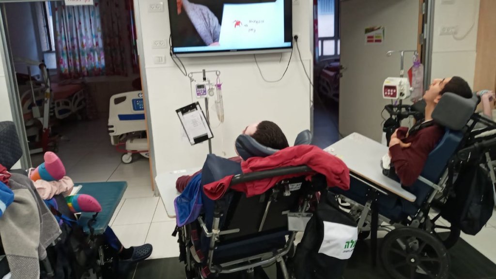 ALEH residents with disabilities watching a video of a children's book being read aloud on a tv screen