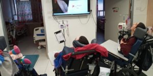 ALEH residents watching a video of a children's book being read aloud on a tv screen