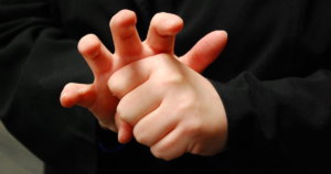 The American Sign Language word for COVID-19 mimics the virus' appearance, with fingers forming the spikes, or coronas, the virus is known for. Photo credit: NCDHHS.