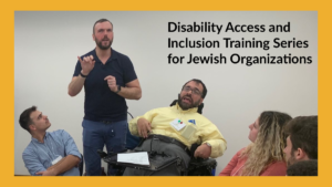A man using a wheelchair next to an ASL interpreter speaks as three other people look on seated. Text: Disability Access and Inclusion Training Series for Jewish Organizations