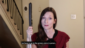 Still from the SNAP Delivery Saves Lives PSA video with a blind woman holding a white cane talking to camera. Subtitle Text: we have to go to the grocery store in person