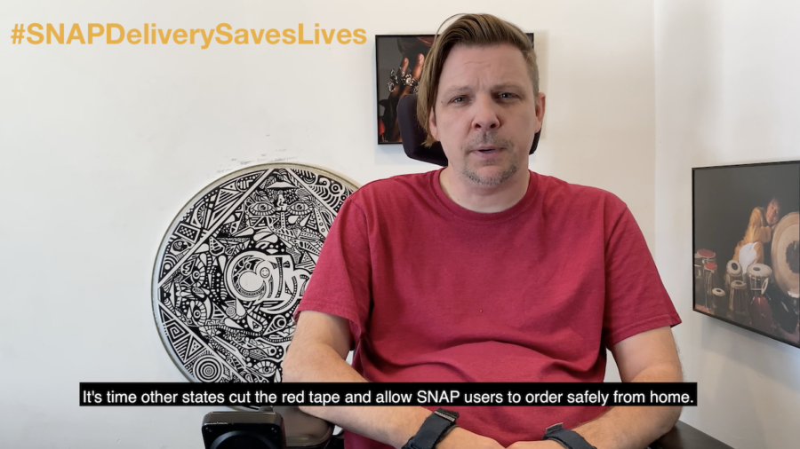 Still from the SNAP Delivery Saves Lives PSA video with a man who uses a wheelchair talking to camera. Text: #SNAPDeliverySavesLives. Subtitle Text: It's time other states cut the red tape and allow SNAP users to order safely from home.