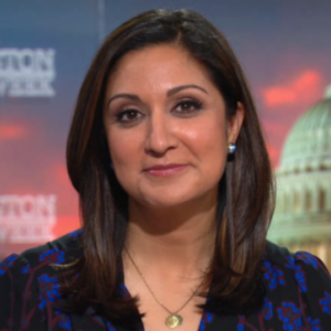 Amna Nawaz smiling headshot on the PBS NewsHour set.