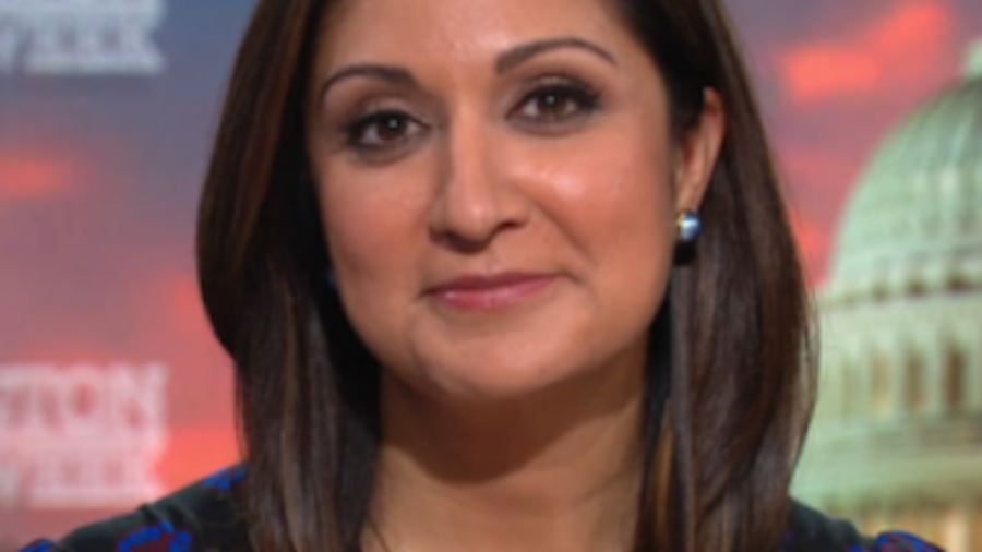 Amna Nawaz smiling headshot on the PBS NewsHour set.