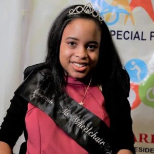 Ketrina Hazell headshot smiling wearing a sash that says Ms. Wheelchair New York on it