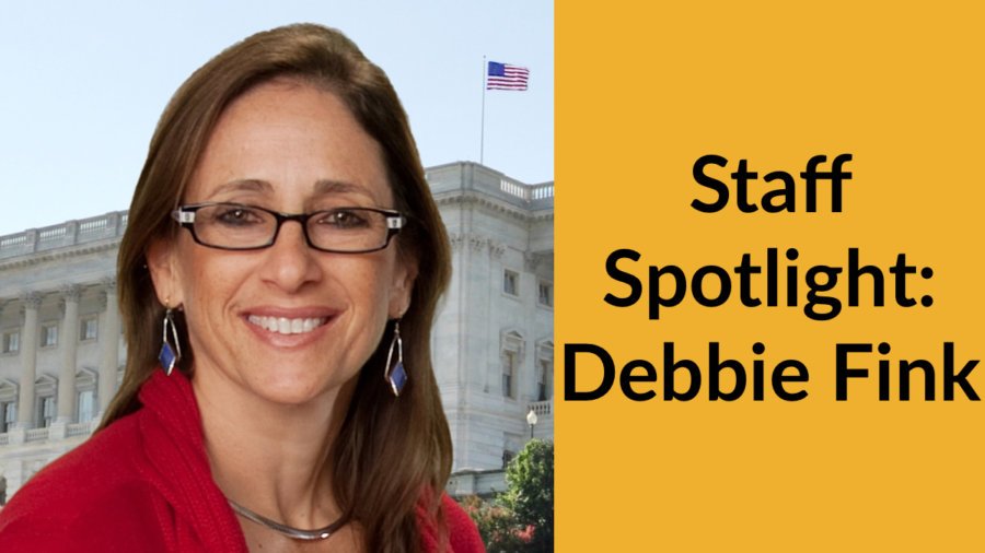 Debbie Fink smiling headshot in front of an American flag and a government building. Text: Staff Spotlight: Debbie Fink