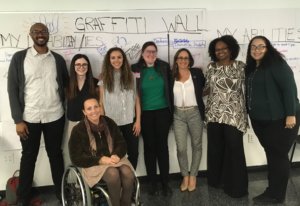 Debbie Fink with presenters and facilitators at training for Female College Students with Disabilities in front of a graffiti wall smiling together