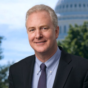 Chris Van Hollen smiling wearing a suit and tie with the US Capitol dome in the background behind him.