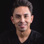 Danny Gomez smiling headshot wearing a black shirt in front of a black backdrop