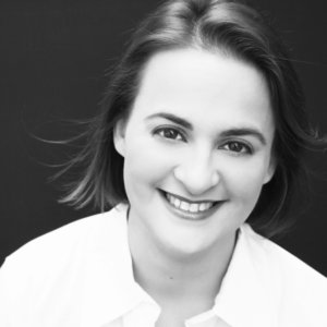 Elisabeth J Finch smiling black and white headshot. Elisabeth is a white woman with dark hair