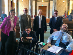 Six people, two of whom use wheelchairs, in a hearing room in Los Angeles together