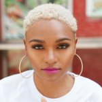 Lolo Spencer smiling headshot. Lolo is a woman of color with short hair and hoop earrings