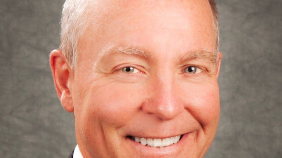 Mark Allan Schultz smiling wearing a suit. Schultz is a white man with very short hair