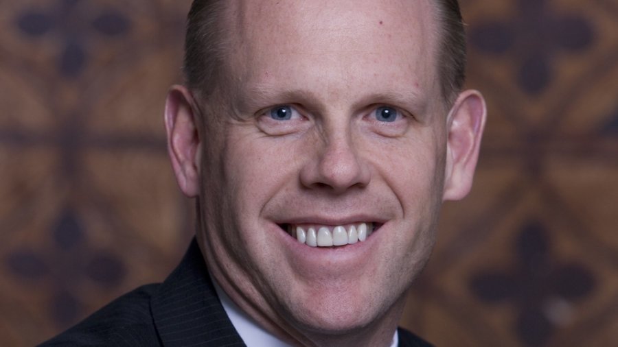 Mark Feinour smiling wearing a suit and tie. Mark is a white man with short brown hair.