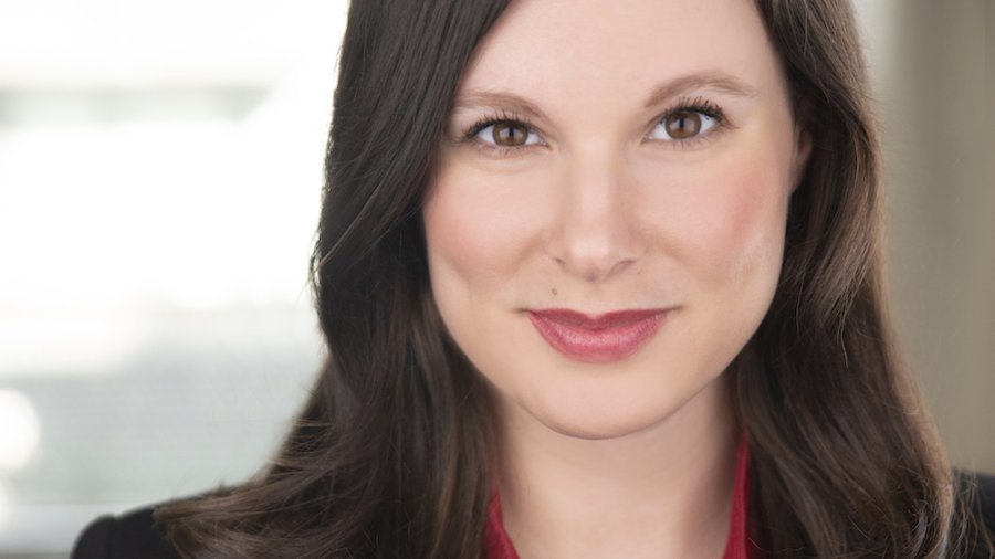 Rachel Handler smiling headshot. Rachel is a white woman with brown hair down to her shoulders, and is wearing a black jacket and red shirt