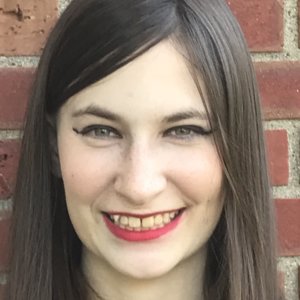 Stephanie Santo smiling in front of a brick wall