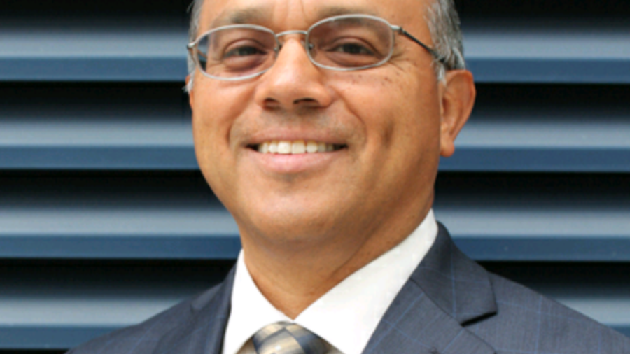 Jaime Pacheco Orozco smiling wearing a suit and tie and glasses. Jaime has short black hair