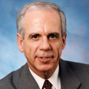 Hon. Tony Coelho headshot wearing a suit and tie. Coelho is a white man with short grey hair