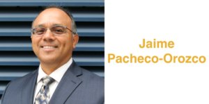 Jaime Pacheco Orozco smiling wearing a suit and tie and glasses. Jaime has short black hair. Text: Jaime Pacheco-Orozco