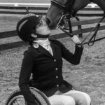 Alanna Flax-Clark with a horse kissing her face. Flax-Clark is a wheelchair user.