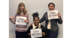 Three RespectAbility team members holding up signs that say "Earn My Vote"