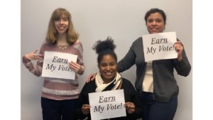 Three RespectAbility team members holding up signs that say "Earn My Vote"