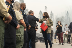 Kamala Harris bumps elbows with a firefighter in Auberry California. Nasreen Alkhateeb is in the background filming