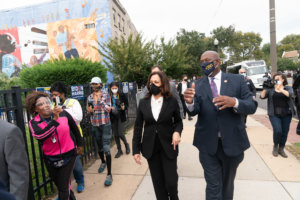 Kamala Harris and Rep. Dwight Evans walk down a sidewalk in Philadelphia. Nasreen is behind them filming