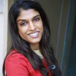 Headshot of Khadija Bari smiling leaning against a wall