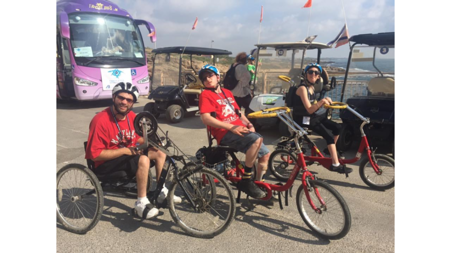 Blair Webb and two other participants on the birthright trip riding accessible bicycles in front of a large body of water