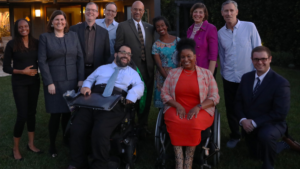 A group of diverse people with and without disabilities smiling together outside