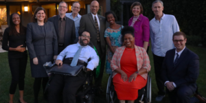 A group of diverse people with and without disabilities smiling together outside