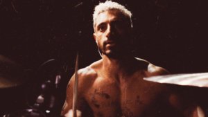 Riz Ahmed shirtless at a drum set in the poster for Sound of Metal