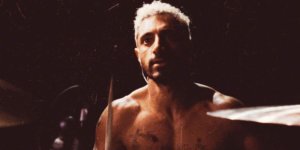 Riz Ahmed shirtless at a drum set in the poster for Sound of Metal