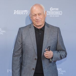 Joey Travolta smiling in front of a banner with the variety logo and Cuervo traditional logo on it