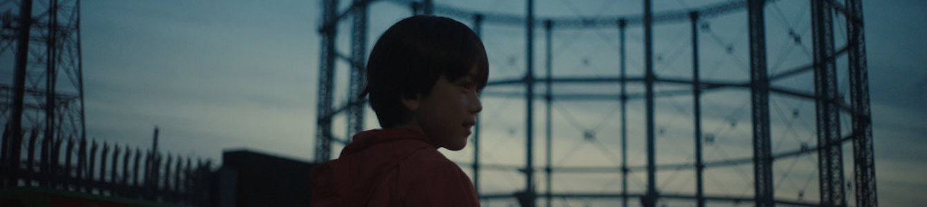 A young boy walking outside in a scene from The Reason I Jump