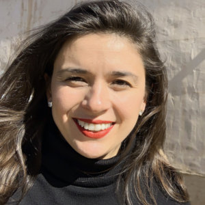 Alexandra Grossi headshot smiling in front of a wall