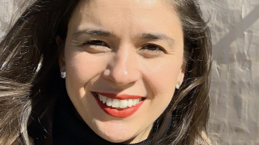 Alexandra Grossi headshot smiling in front of a wall