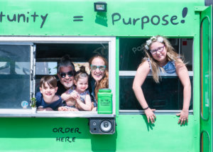 the Chernotsky family looking out the windows in a green bus, smiling