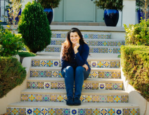 Leah Romond seated on a staircase, smiling.