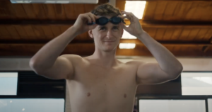 Adam Bowes as Alex putting on swim goggles in a scene from Diving In